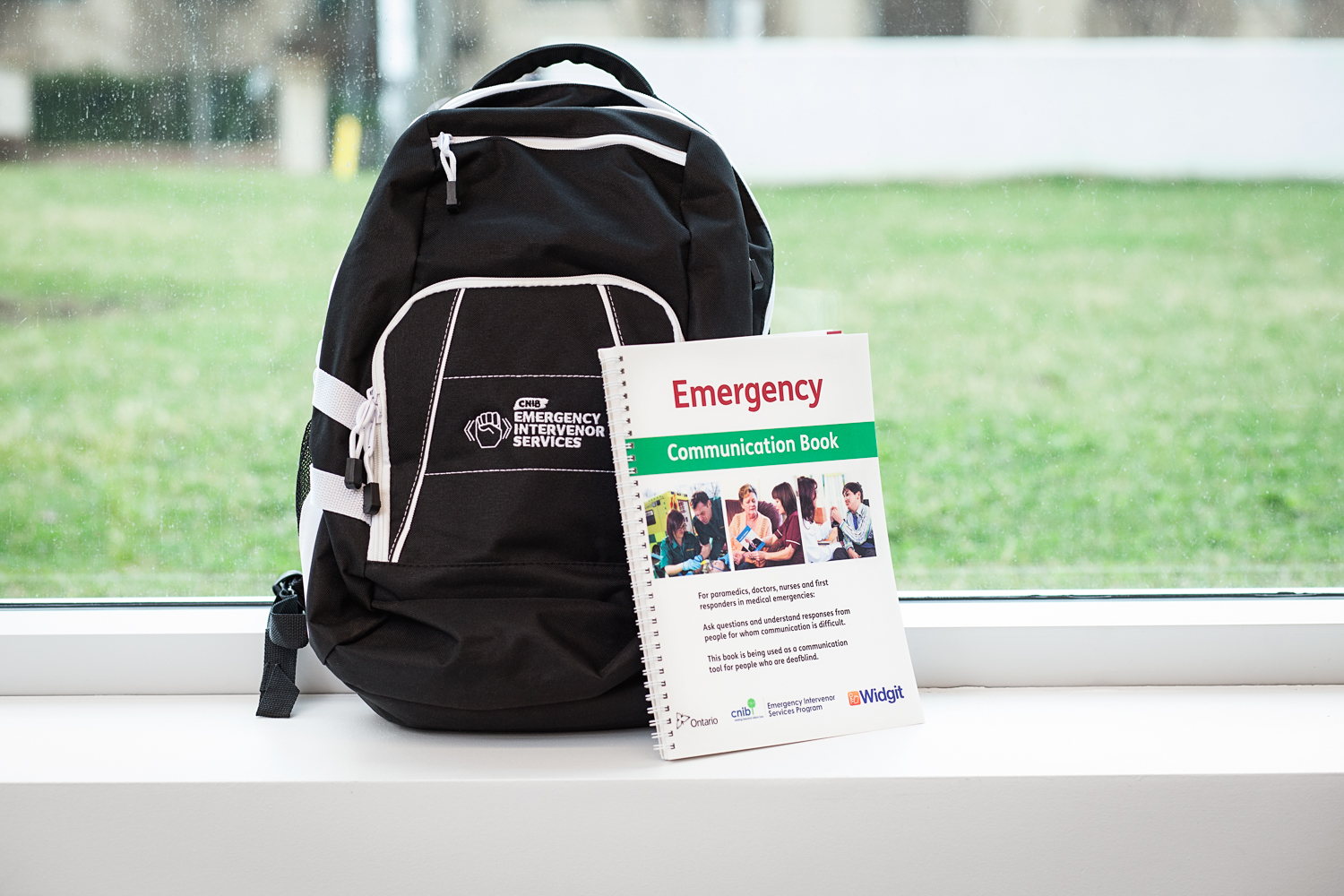 Le kit de communication d'urgence du SCS. Un sac à dos noir et un livre intitulé "Emergency Communication Book".