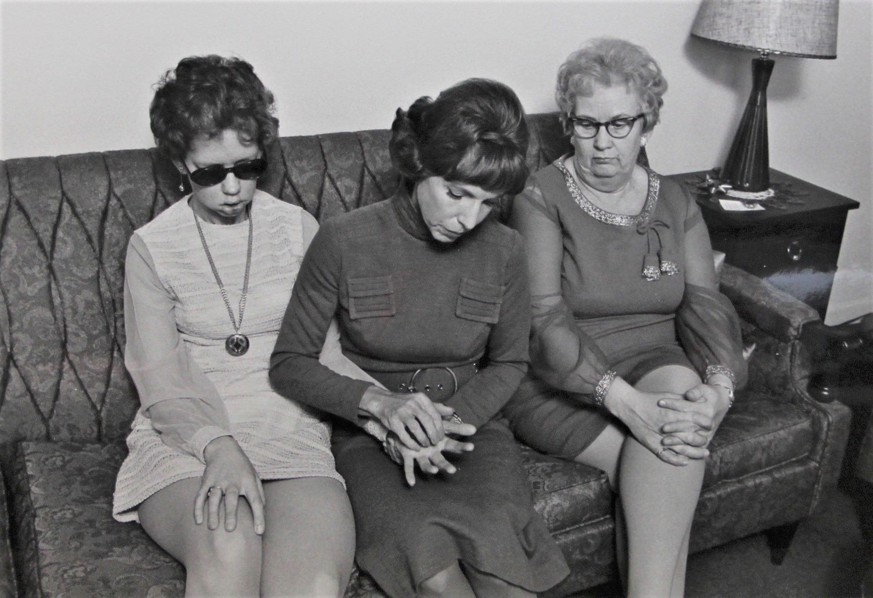 Mae Brown et Joan McTavish sont assises l'une à côté de l'autre sur un canapé. Une autre femme est assise à côté d'elles et regarde le couple communiquer.