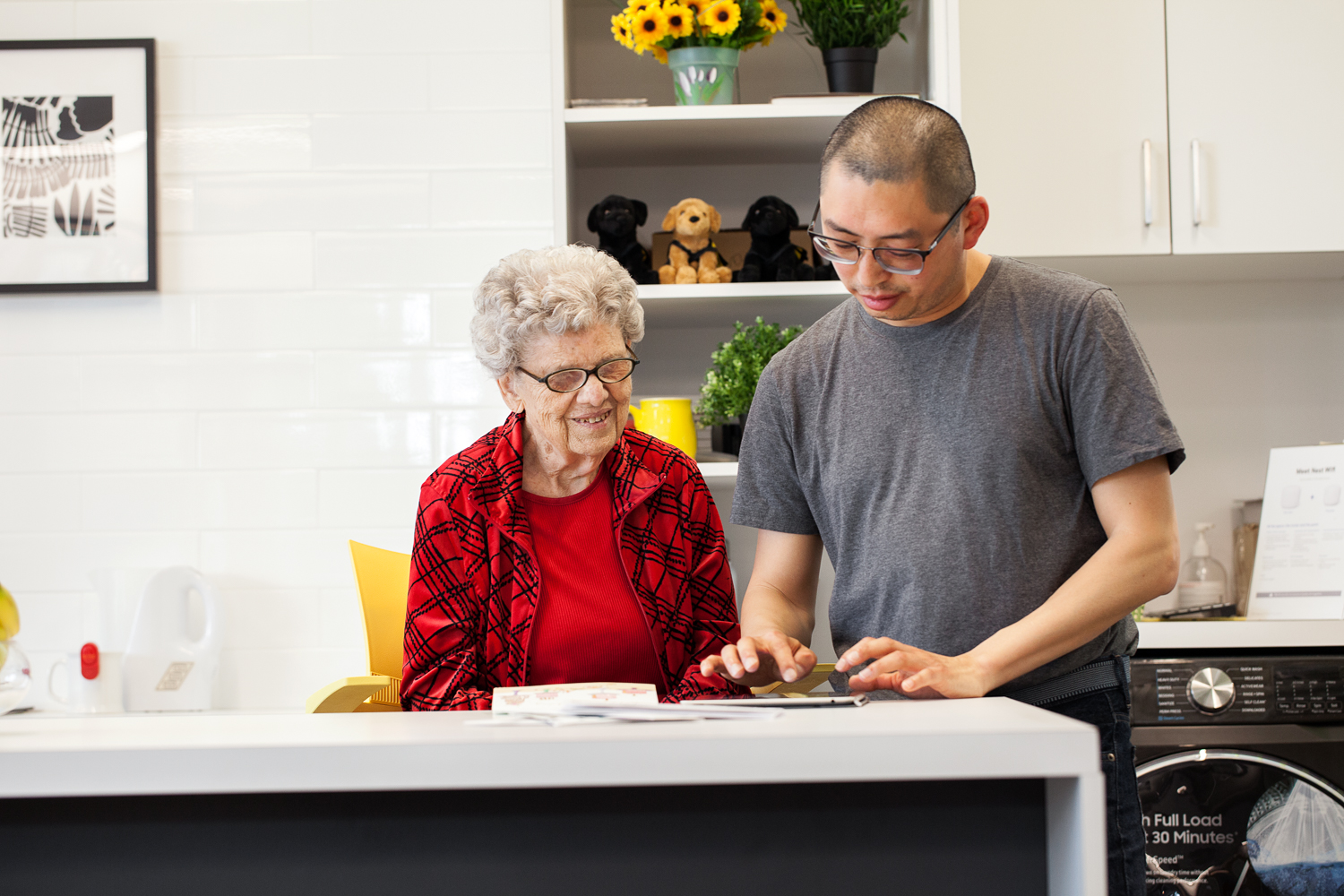 L’accompagnateur et un client sont assis à une cuisine et utilisent une tablette pour communiquer.