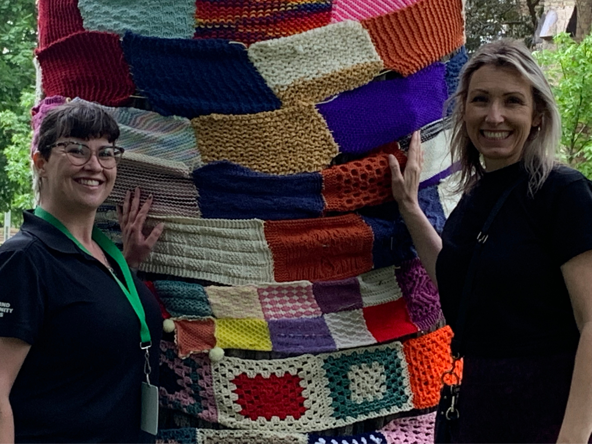 Two staff members pose in front of yarn bombing exhibit 