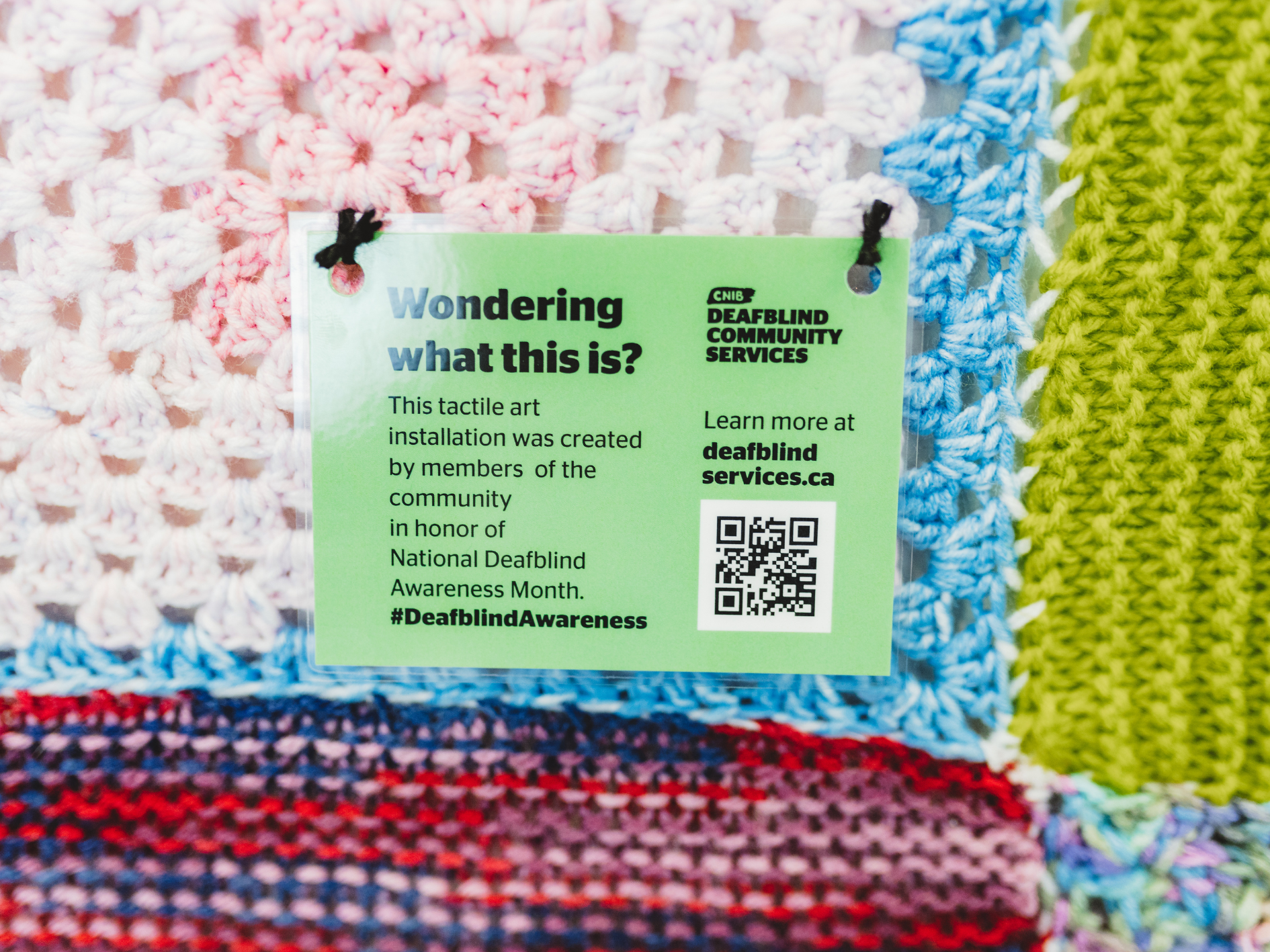 "Wondering what this is" sign on a yarn bombing installation 