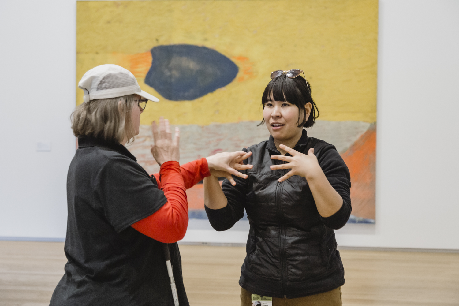 Un employé utilise la langue des signes tactile pour communiquer avec un client sourd-aveugle dans une galerie d'art.
