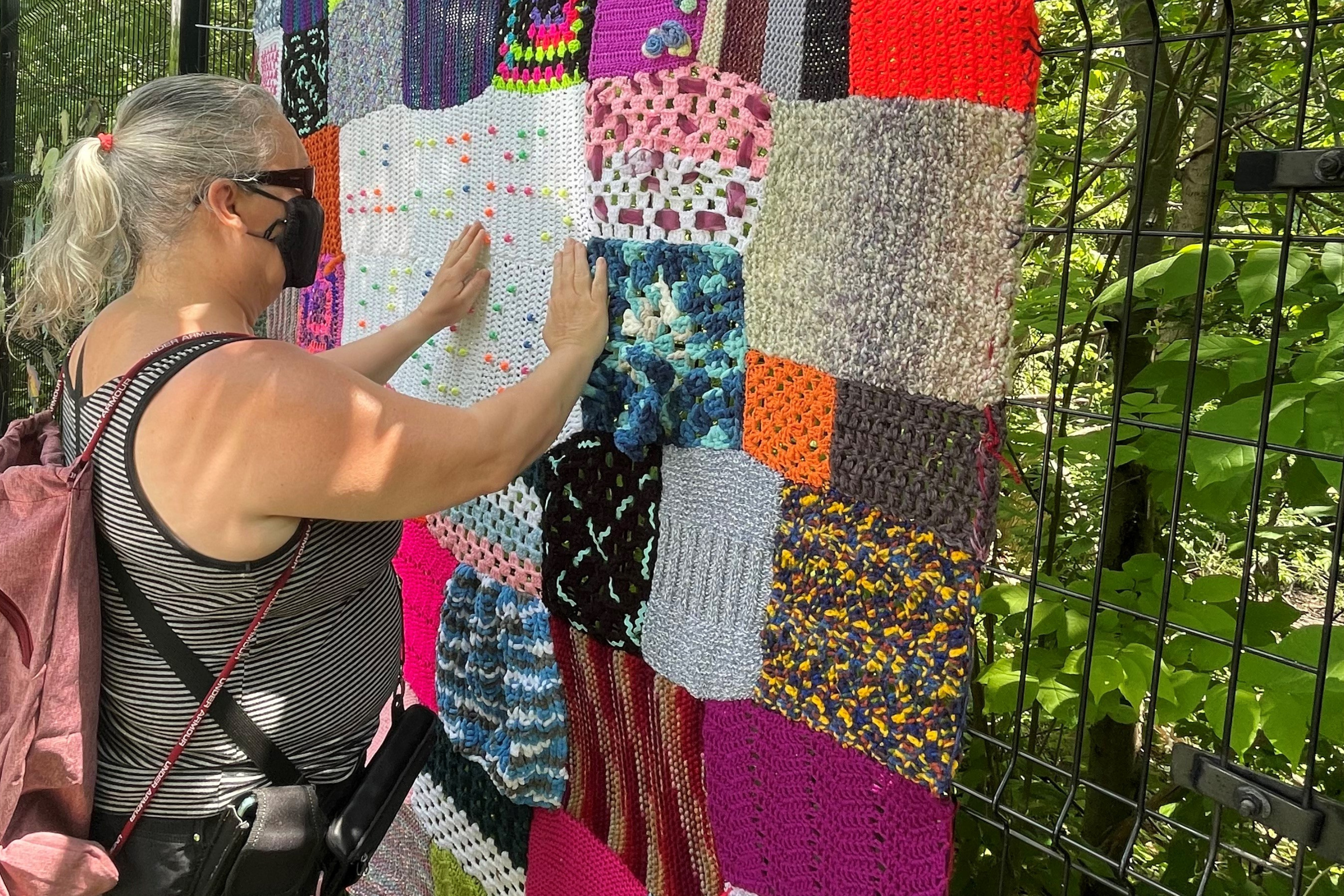 Une femme ressent les textures d'une couverture en fil multicolore.