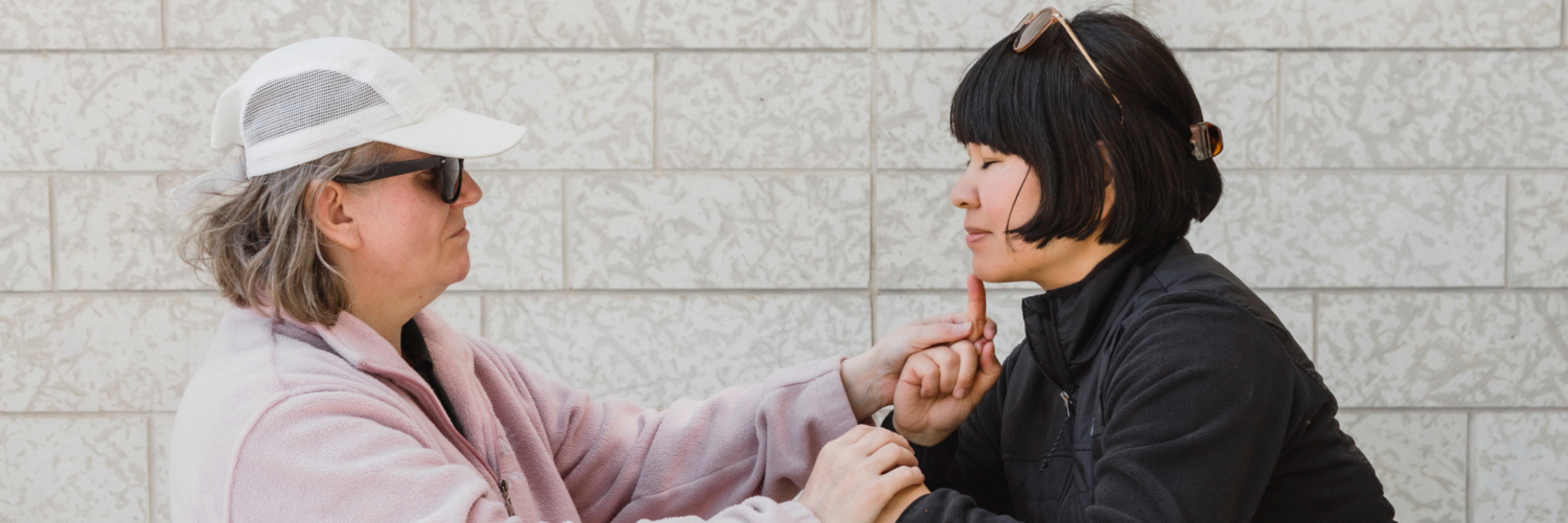 Une femme utilise la langue des signes tactile pour communiquer avec un client sourd et aveugle.