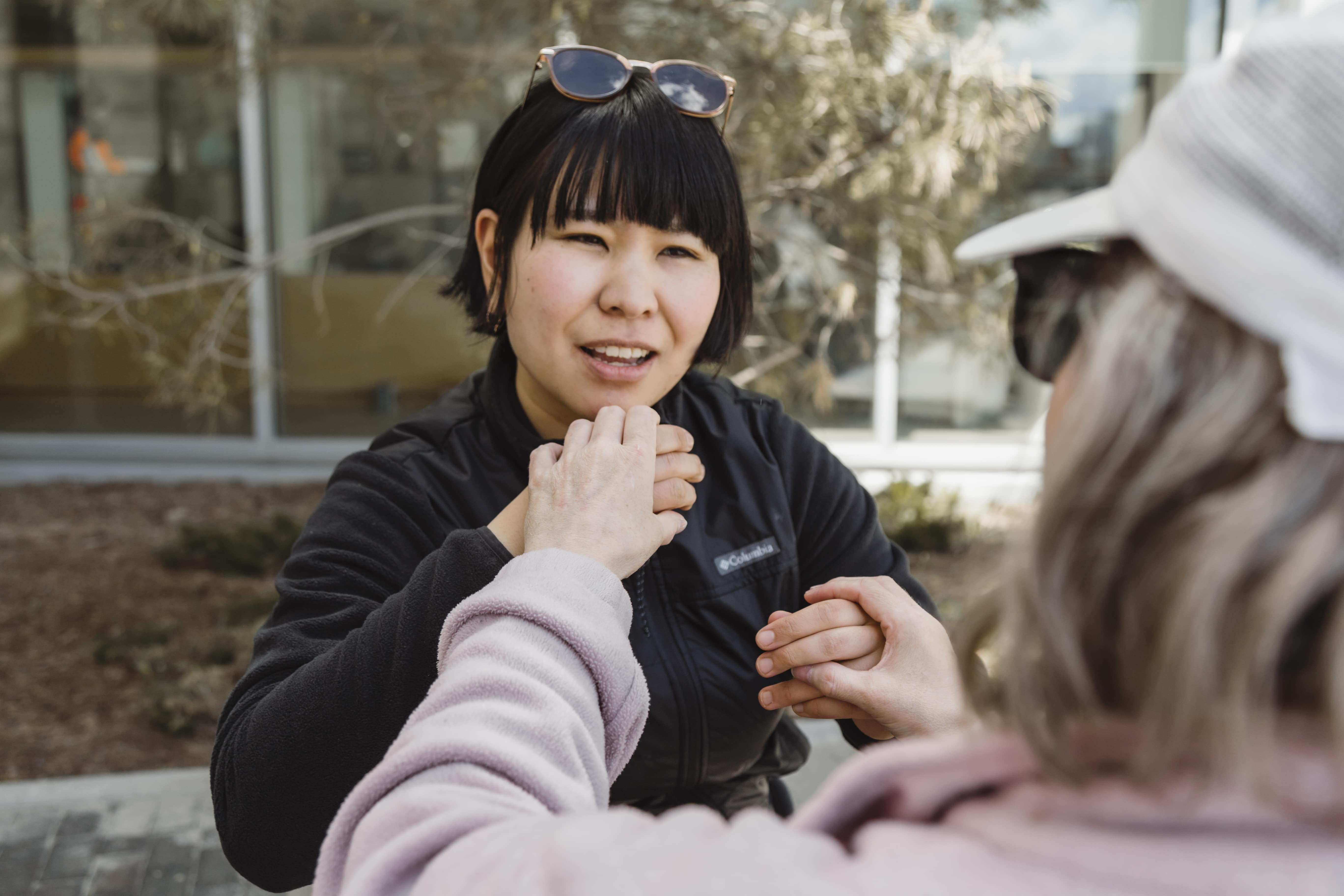 Une accompagnatrice utilise la langue des signes tactile américaine pour converser avec une cliente.