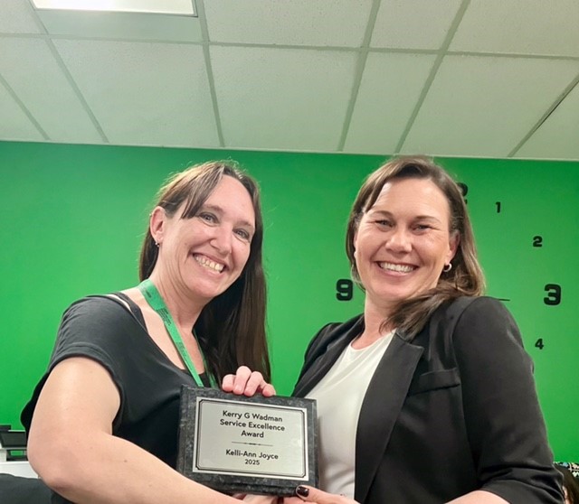 Kelli and Gwen shake hands while holding the KGW winner's plaque.