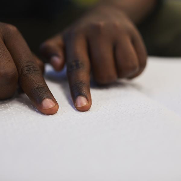 Des mains parcourent un livre en braille.