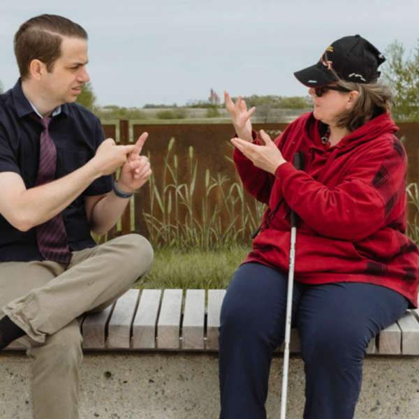 A man and woman have a conversation outside using ASL.